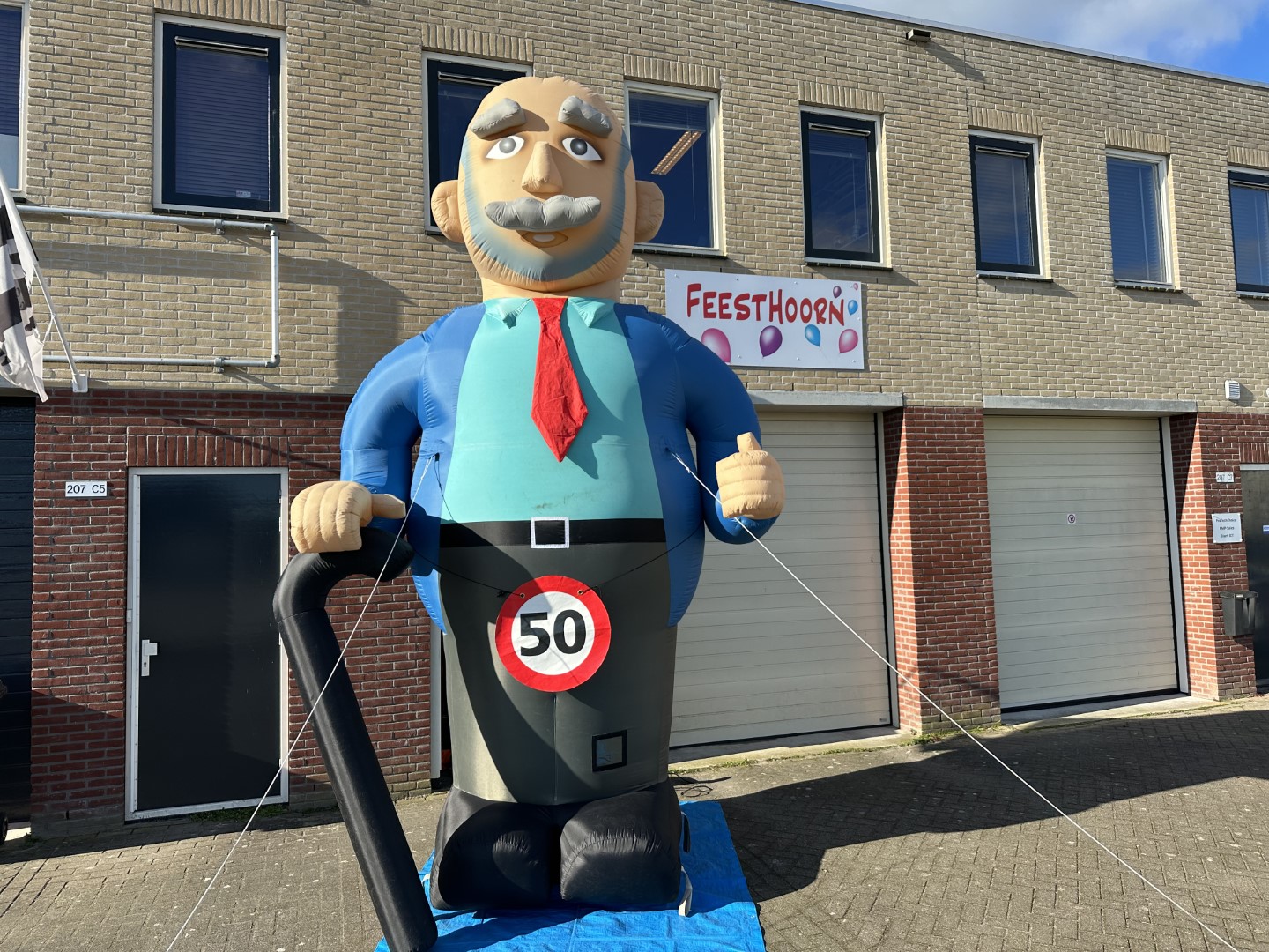 De Abraham XL pop van 4,2 meter hoog met een wandelstok. Geleverd met een verkeersbordbanner naar keuze of een 'pensioen' banner.