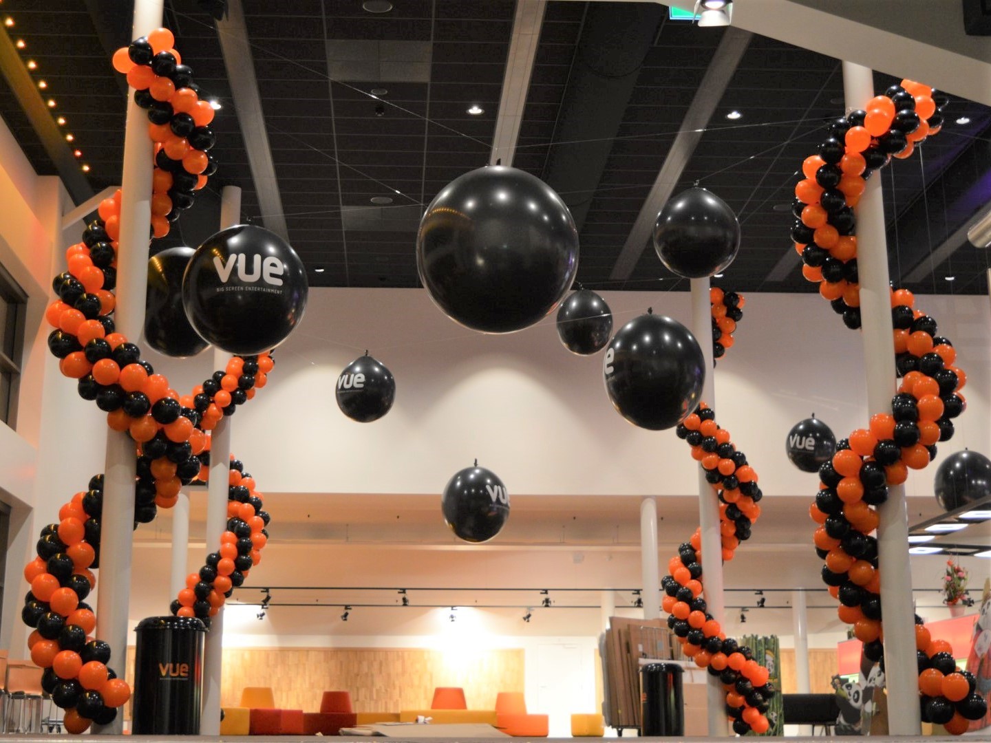 Reuze Bedrukte luchtgevulde ballonnen aan nylondraad hangend aan het plafond met ballonnenguirlandes om steunpilaren gemonteerd.