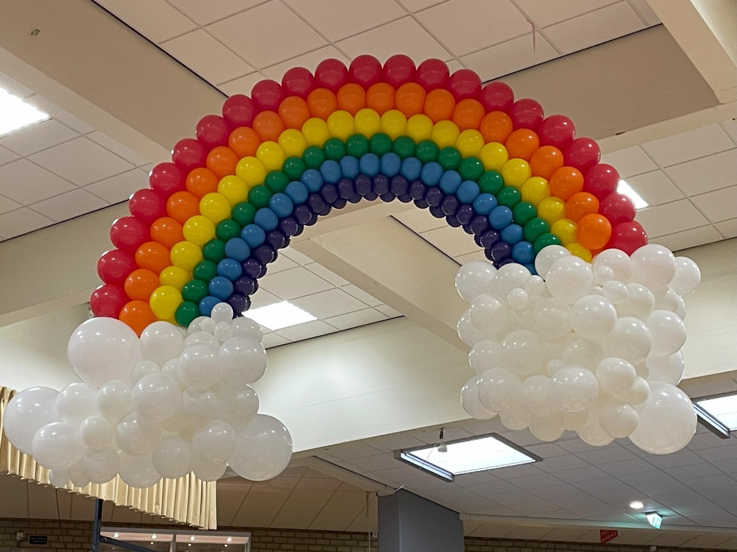 Regenboog van ballonnen met organische ballonwolken. om op te hangen of op een verzwaard structuur te plaatsen.