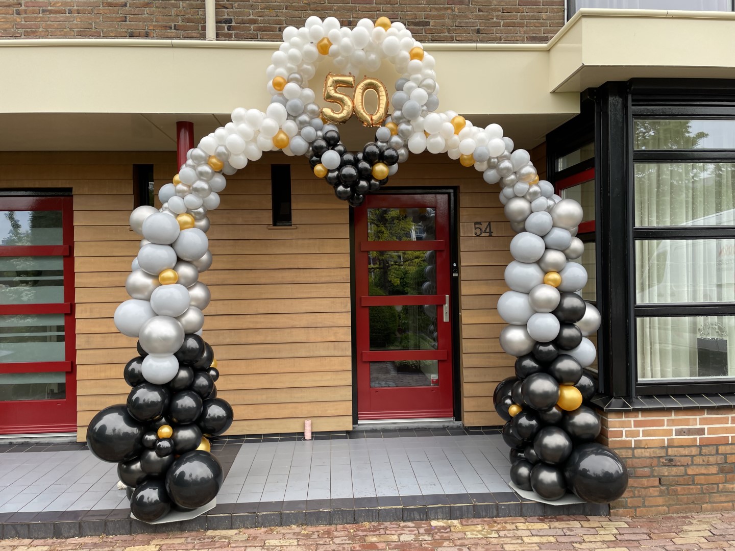 Organische Hartboog. Verschillende maten en kleuren ballonnen met een hart in het midden. Eventueel ook aan te vullen met foliecijfers.